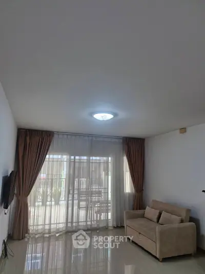 Spacious living room with elegant curtains and cozy sofa, perfect for relaxation.