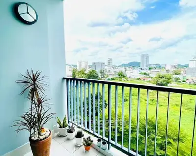 Spacious balcony with stunning cityscape view and lush greenery, perfect for relaxation and enjoying nature.