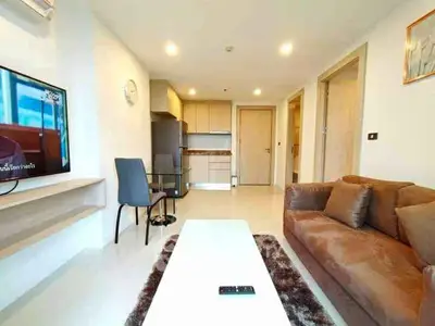 Modern living room with cozy brown sofa, sleek kitchen, and dining area in open layout apartment.