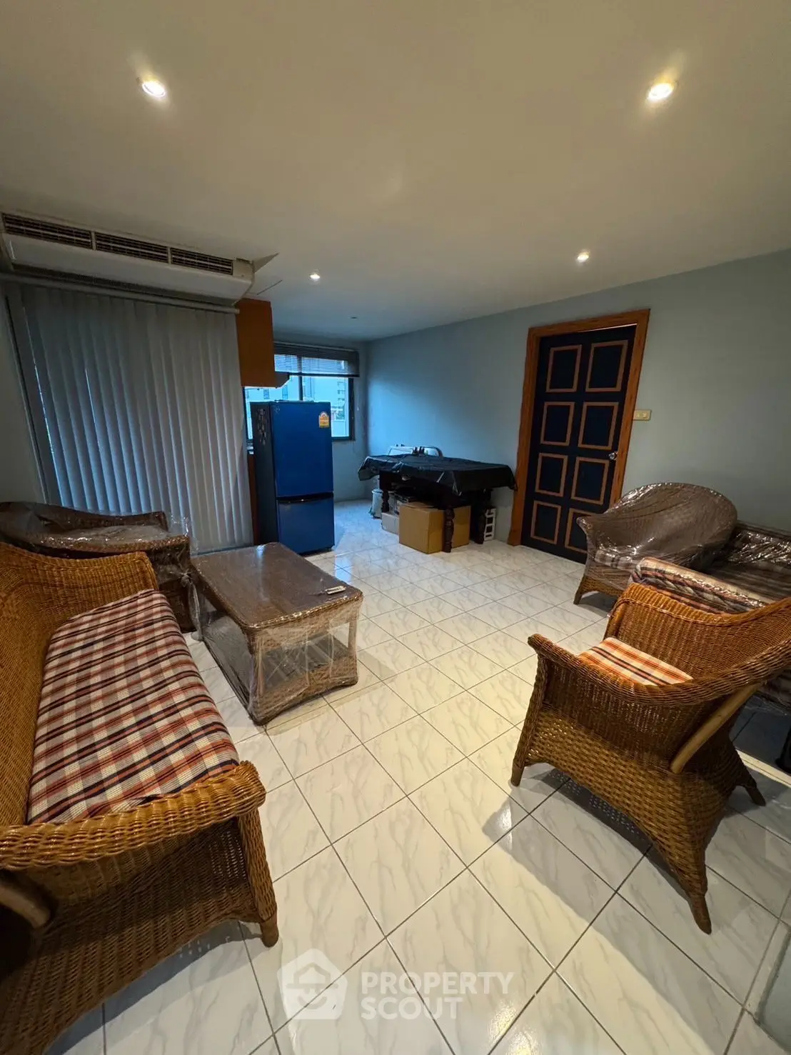 Cozy living room with wicker furniture and tiled flooring, featuring a compact layout.