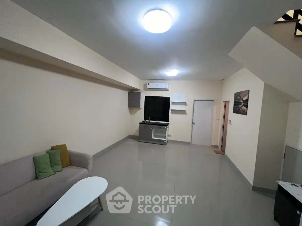 Spacious living room with modern decor and ample lighting, perfect for relaxation and entertainment.