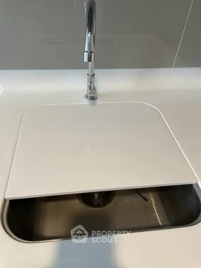 Modern kitchen sink with sleek cover and chrome faucet in contemporary design.