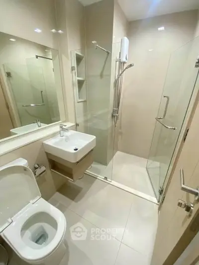 Modern bathroom with glass shower and sleek fixtures in contemporary apartment.