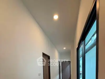 Modern hallway with recessed lighting and wooden doors in a contemporary apartment.