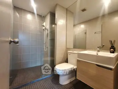 Modern bathroom with glass shower and sleek fixtures in contemporary apartment.