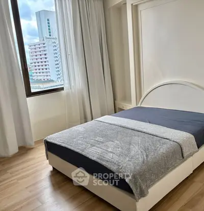 Cozy bedroom with city view, featuring a modern bed and large window for natural light.