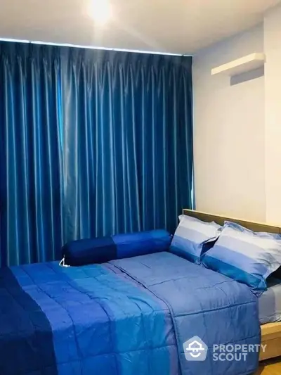 Cozy bedroom with a large comfortable bed, elegant blue bedding, and matching curtains, perfect for restful nights in a modern home.