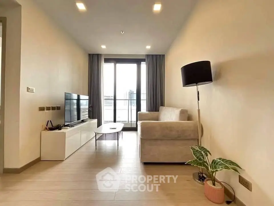 Modern living room with sleek furniture and large window offering city view.