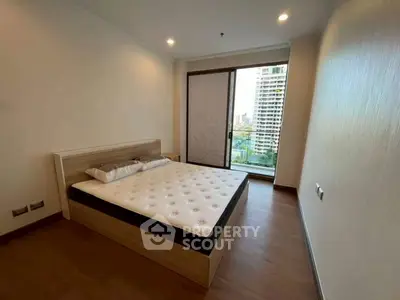 Modern bedroom with large window and city view in high-rise apartment.