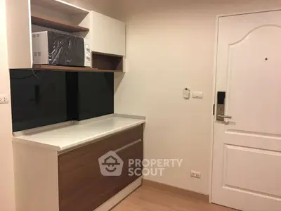 Compact kitchen area with modern cabinetry and microwave, ideal for small apartments.