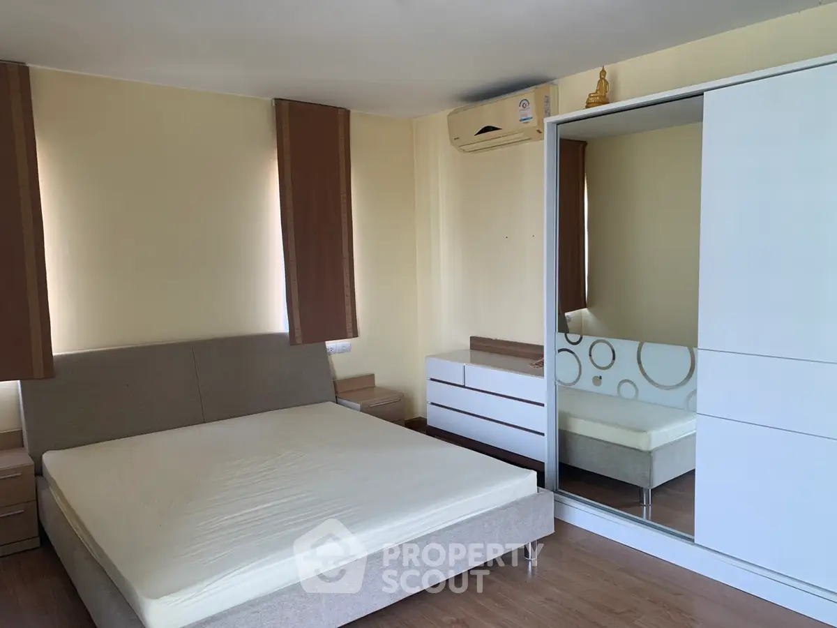 Spacious bedroom with modern furniture and large mirrored wardrobe