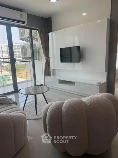 Modern living room with cozy seating and balcony view in urban apartment.
