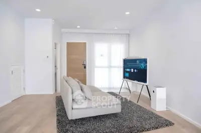Modern minimalist living room with sleek furniture and large TV, perfect for relaxation.