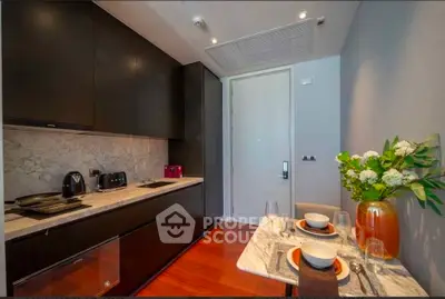 Modern kitchen with sleek black cabinets and marble countertops, featuring a cozy dining area with elegant table setting.