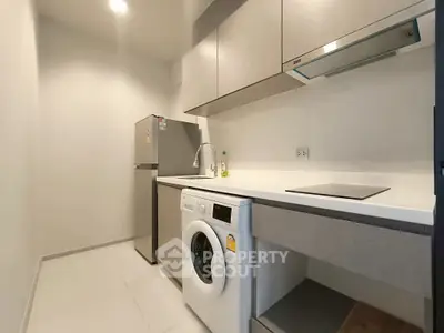 Modern kitchen with sleek cabinetry, washing machine, and stainless steel fridge.