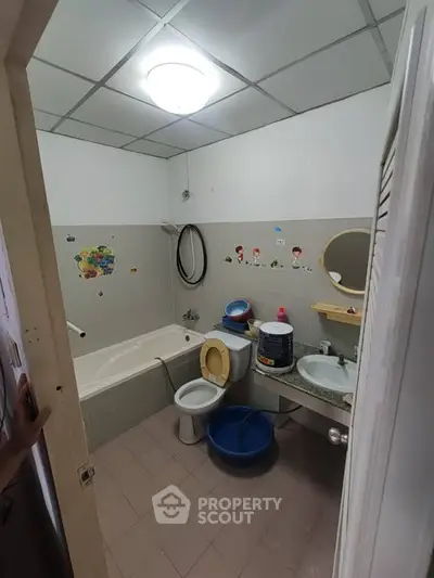 Cozy bathroom with bathtub, sink, and toilet, featuring playful wall stickers.