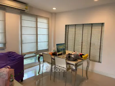 Modern dining area with elegant table and chairs, bright natural light from large windows.