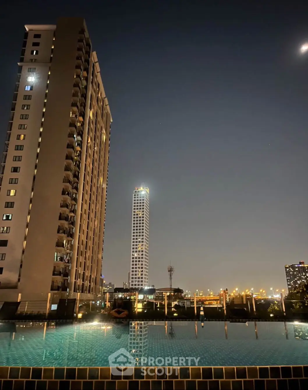 Stunning night view of city skyline from rooftop pool, perfect for urban living.