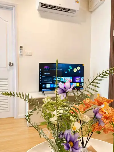 Cozy living room with modern TV setup and vibrant floral decor, perfect for relaxation.