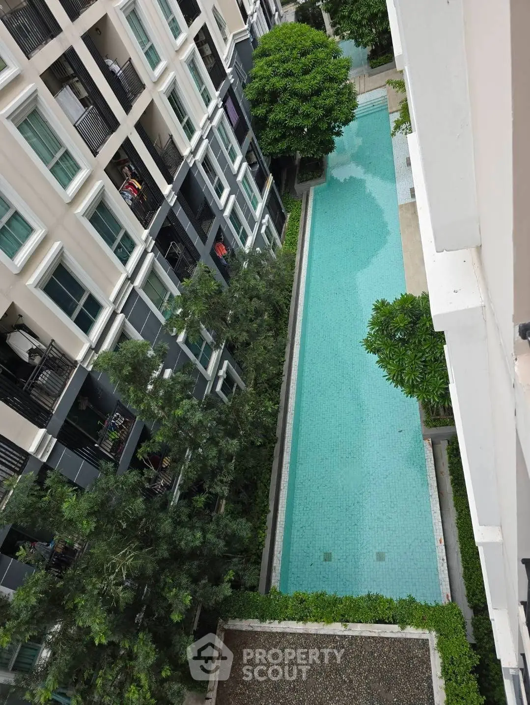 Stunning aerial view of modern apartment complex with inviting swimming pool and lush greenery.