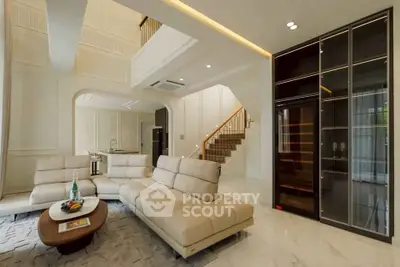 Luxurious modern living room with elegant furniture and open kitchen layout, featuring a stylish staircase.