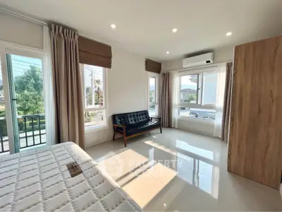 Spacious bedroom with large windows and modern furnishings, offering a bright and airy atmosphere.