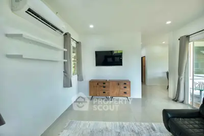 Modern living room with wall-mounted TV and air conditioning, featuring sleek furniture and neutral decor.