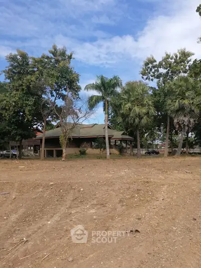 Charming rustic house surrounded by lush greenery and tall trees, offering serene natural views.