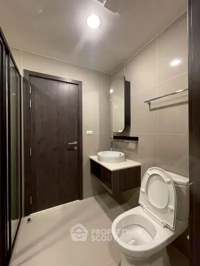 Modern bathroom with sleek fixtures and neutral tones, featuring a shower and elegant vanity.