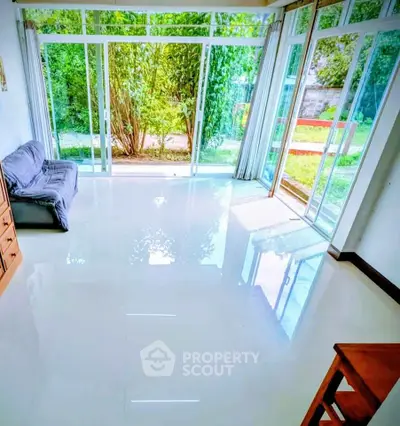 Spacious living room with large windows and garden view, perfect for natural light lovers.