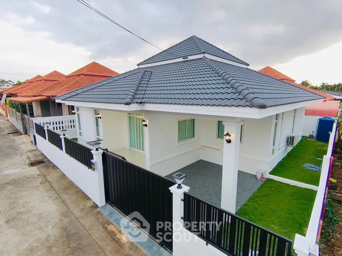 Charming modern house with stylish roof and lush green lawn in a serene neighborhood.