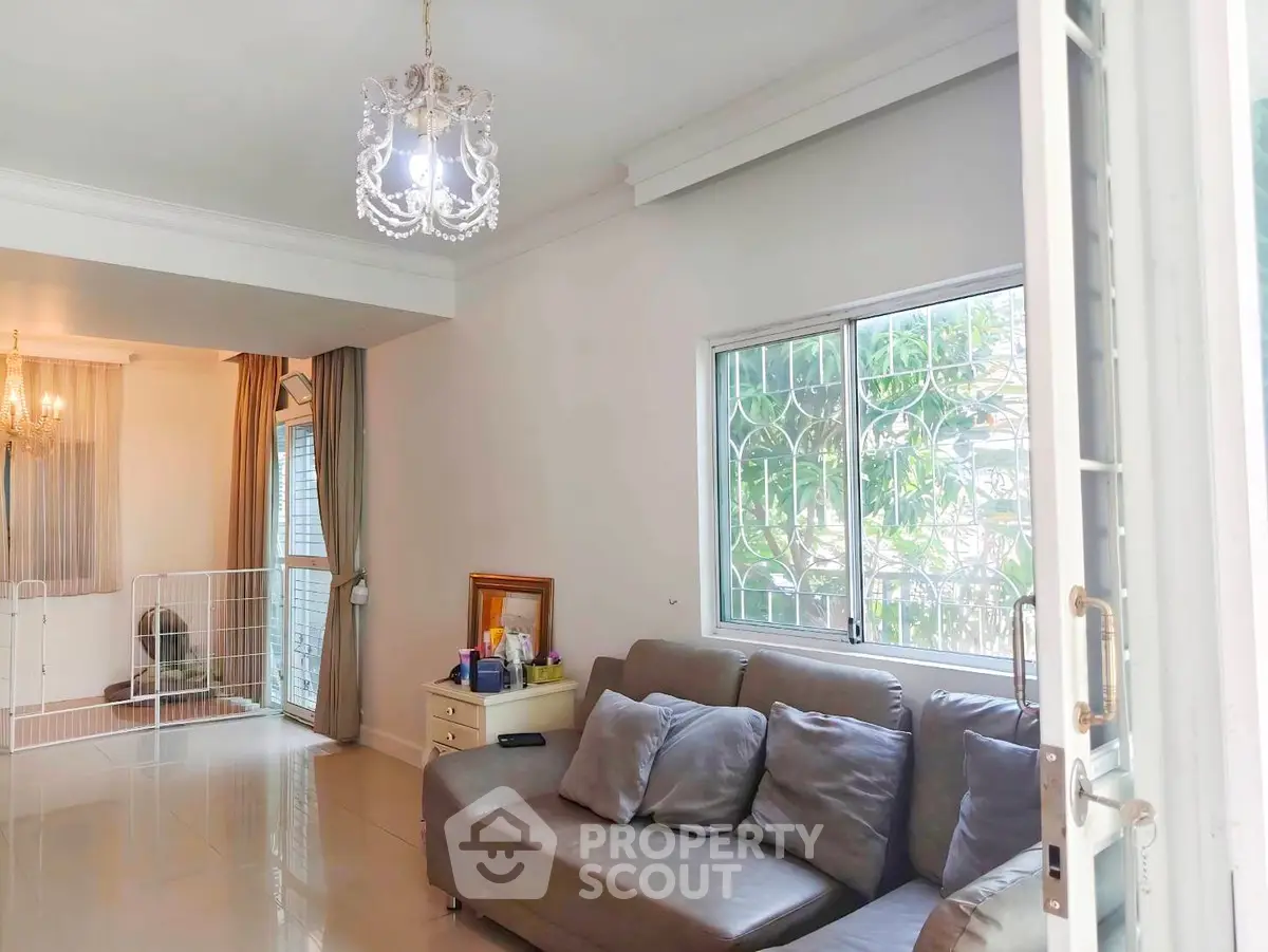 Spacious living room with elegant chandelier and cozy seating area, perfect for relaxation and entertaining.