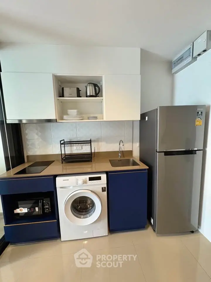 Modern kitchen with sleek appliances including washing machine and fridge, ideal for urban living.