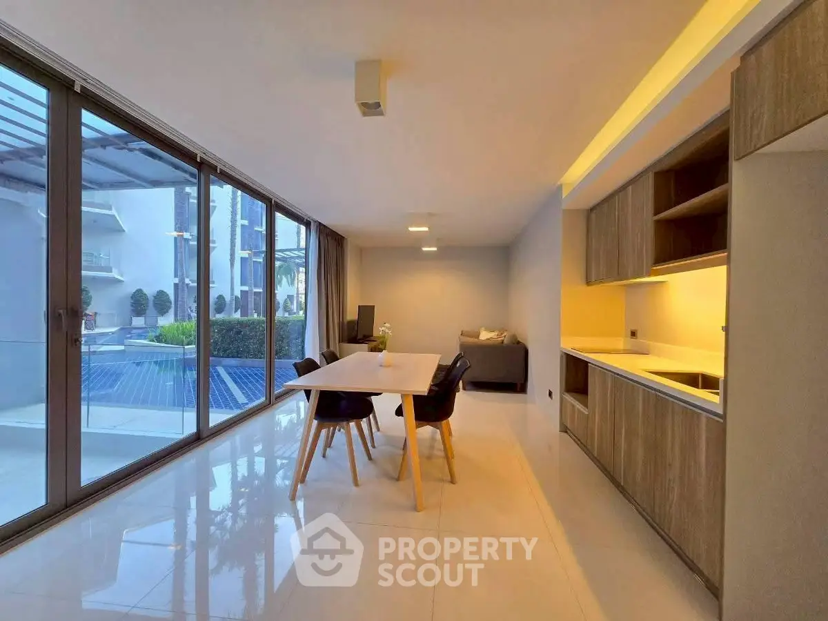Spacious modern living room with open kitchen and large windows overlooking a terrace.