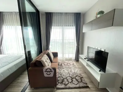 Modern living room with cozy sofa, TV, and large windows in a stylish apartment.