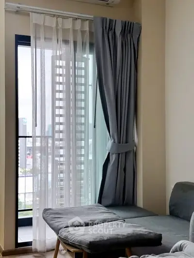 Modern living room with large window and city view, featuring stylish curtains and cozy seating.