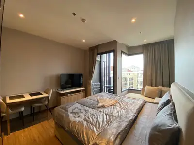 Modern bedroom with balcony and city view, featuring cozy seating area and TV.
