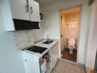 Compact kitchen with adjacent bathroom in modern apartment