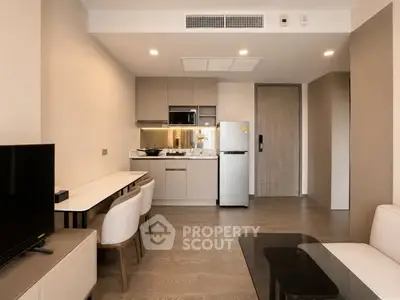 Modern apartment interior with open kitchen and cozy living area, featuring sleek furniture and neutral tones.