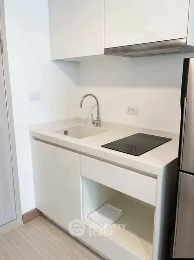 Modern minimalist kitchen with sleek cabinetry and built-in cooktop in a compact space.