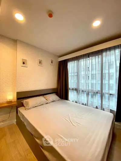 Cozy bedroom with large window and modern decor in urban apartment.