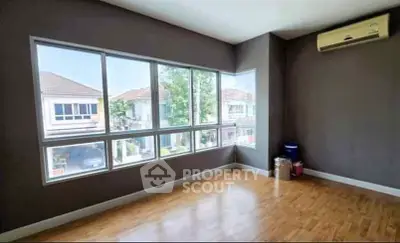 Spacious empty room with large windows and wooden flooring, perfect for customization.