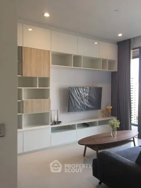 Modern living room with sleek built-in storage and large TV, perfect for stylish urban living.