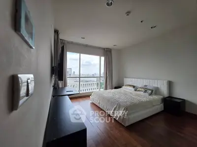 Spacious bedroom with large window offering stunning city views and elegant wooden flooring.