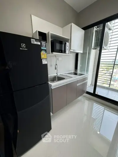 Modern kitchen with sleek appliances and balcony view in stylish apartment.