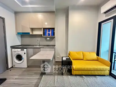 Modern studio apartment with compact kitchen and vibrant yellow sofa