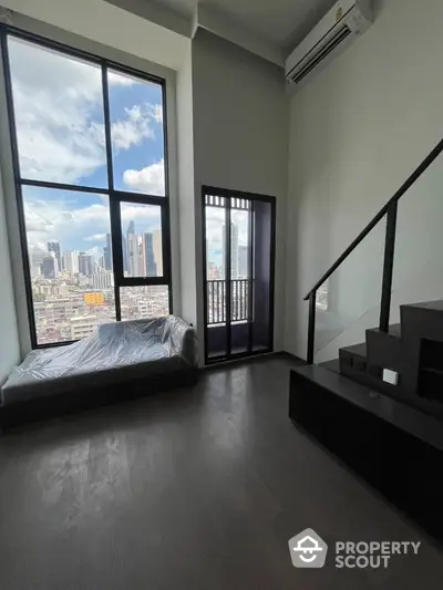 Modern loft apartment with large windows and city view, featuring sleek staircase and minimalist design.