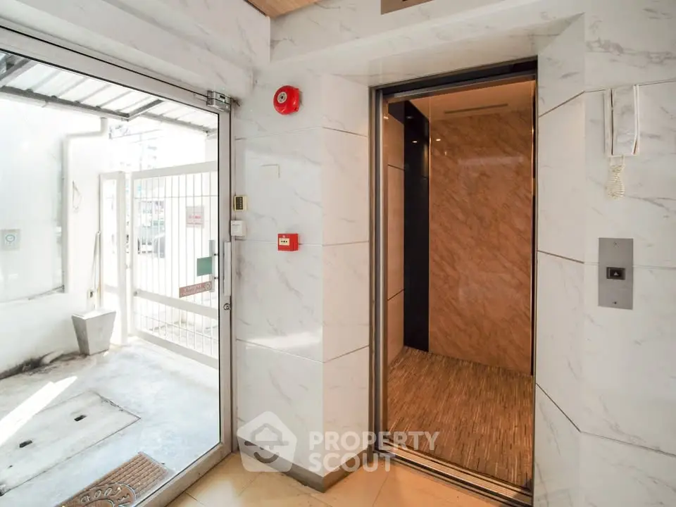 Modern building entrance with sleek elevator and marble walls