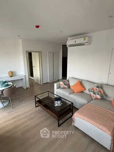 Modern living room with cozy sofa and dining area, featuring stylish decor and air conditioning.