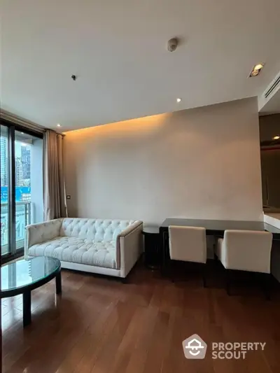 Modern living room with city view, elegant white sofa, and wooden flooring in luxury apartment.